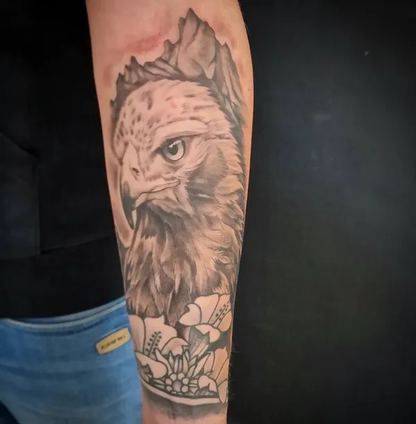 Adlerkopf, Berglandschaft und Blüten als zusammenhängendes Armtattoo