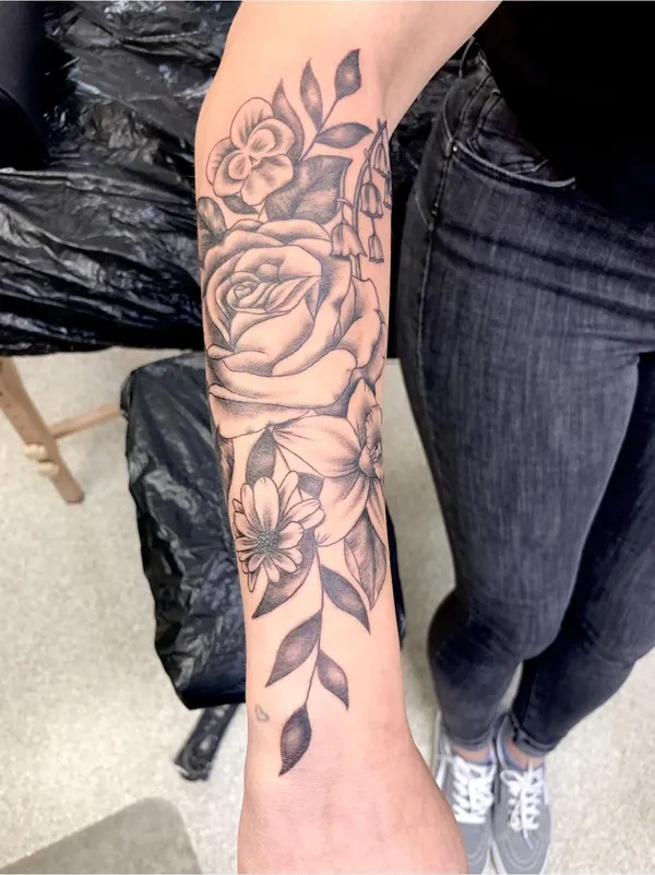 Große Rose und weitere Blüten als florales Unterarmtattoo