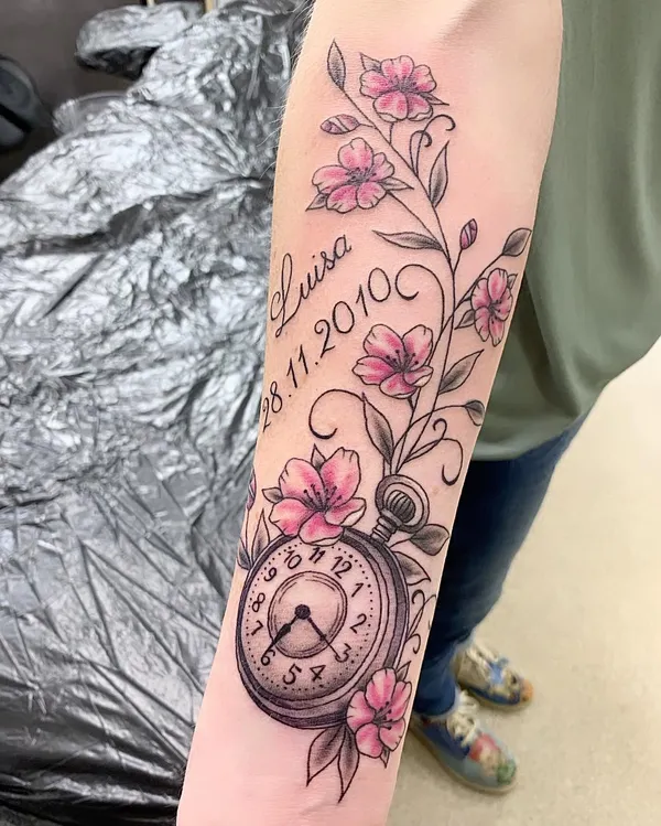 Taschenuhr mit rosa Blüten, Namen und Datum am Unterarm